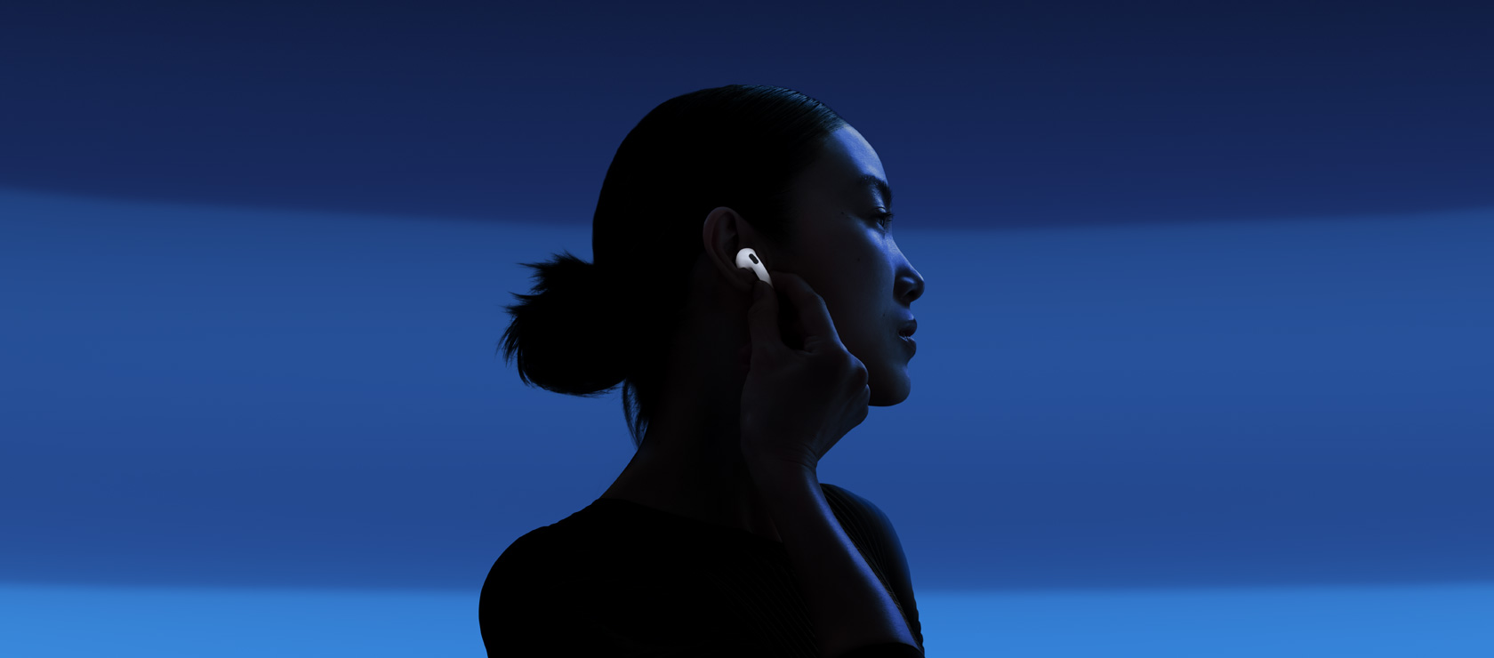 Une personne touchant la tige d’un écouteur AirPods 5 pour activer la Réduction active du bruit