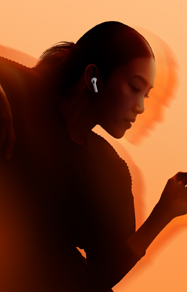 Une personne portant des AirPods 5, les bras pliés, sur un fond multicolore