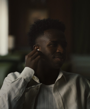 AirPods Pro 3를 착용한 채 흰색 셔츠를 입은 사람이 오른쪽 이어버드를 꼬집고 있는 모습