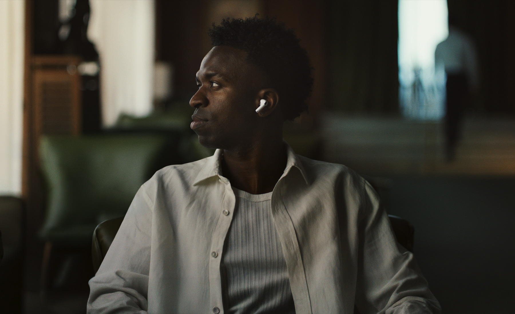 흰색 셔츠를 입고 야외에 있는 사람의 모습. 왼쪽 AirPods Pro 3 이어버드가 보입니다.